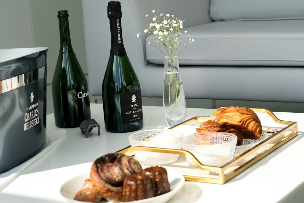 A table topped with a tray of pastries and bottles of wine