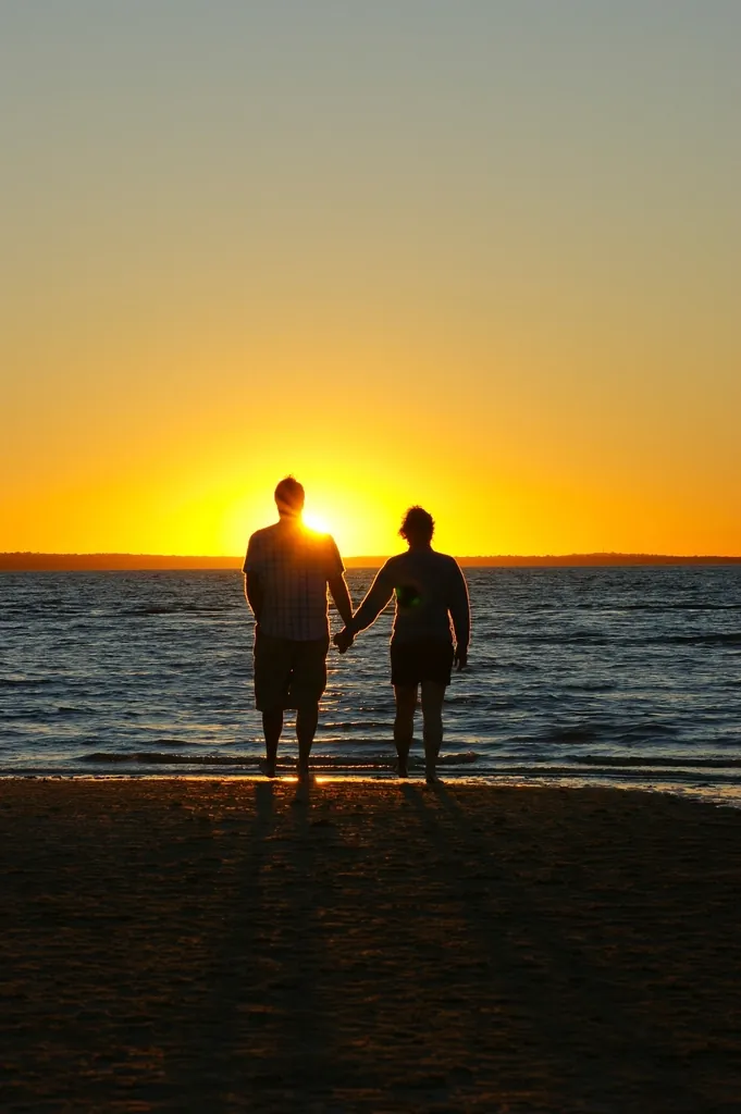 Couple holding hands on the beach at sunset